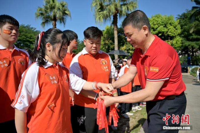 資料圖：廣西華僑實(shí)驗(yàn)高中的教師為高三學(xué)子系上紅絲帶，盼望學(xué)子高考必勝。 俞靖 攝